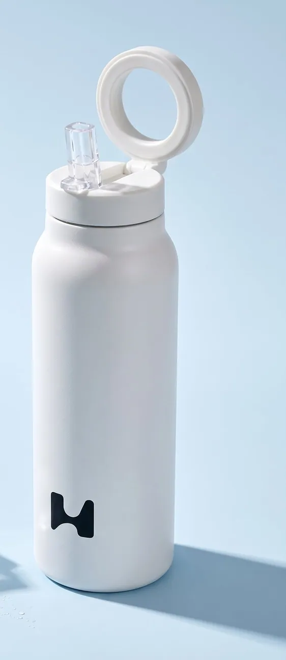 White bottle with the straw lid and its ring raised, on pale blue with ice cubes