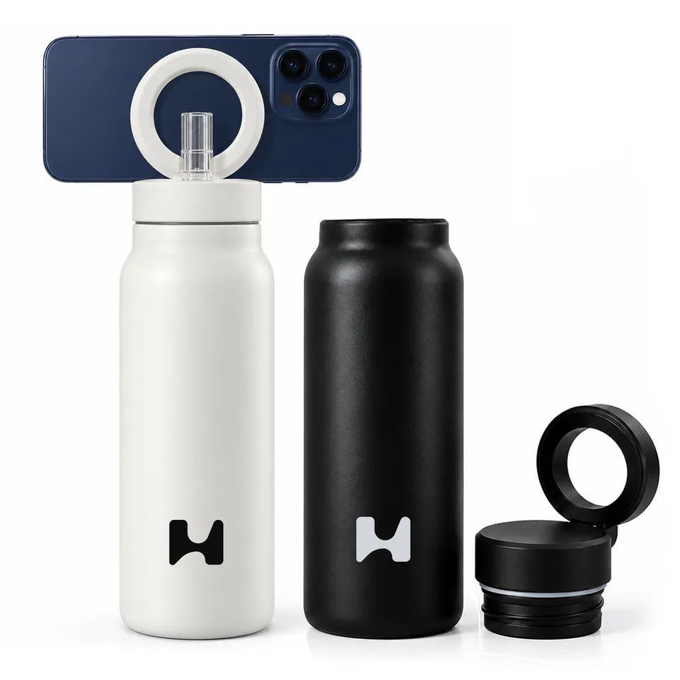 The white bottle holding a phone, the black bottle beside it, and the non-straw lid off to show the ring on its hinge